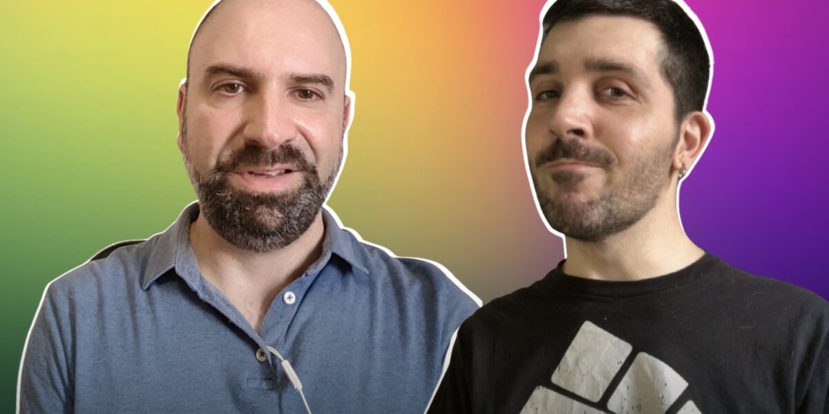 Ritratto mio e di Fabrizio su uno sfondo arcobaleno. Fabrizio ha i capelli rasati, il pizzetto e una polo grigia. Io i capelli corti scuri, la barba corta e una maglia nera nera con un pugno bianco.